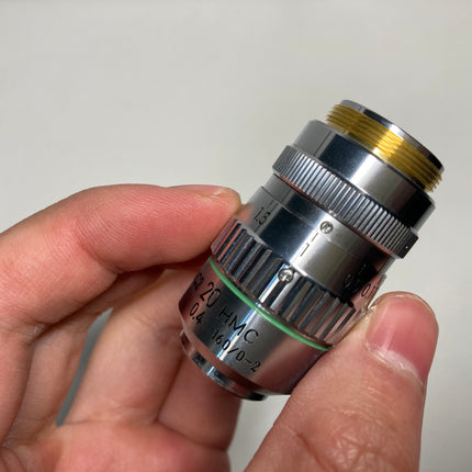 Nikon Objective Hoffman Objective MC2 20x HMC 0.4 160/0-2 RMS held in hand, showcasing detailed design.