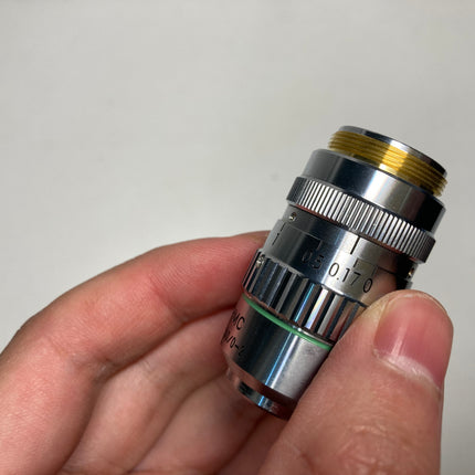 Nikon Objective Hoffman Objective MC2 20x HMC 0.4 160/0-2 RMS in a person's hand, showcasing its detailed design.