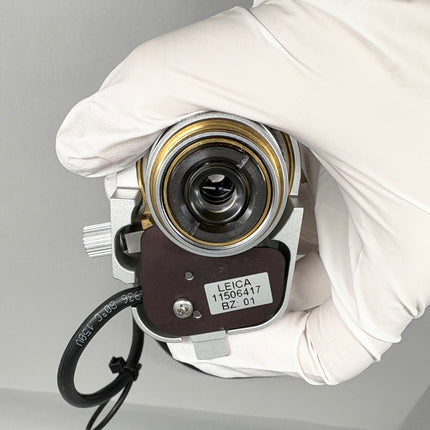 Leica Objective HC PL APO 93x/1,30 GLYC motCORR STED WHITE 506417 held in gloved hand, showing the lens and identification.