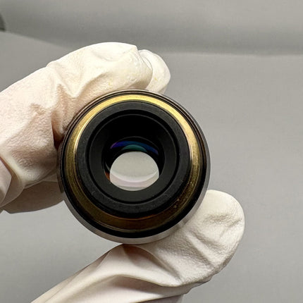 Olympus MPlanApo 20x0.60 ∞/0 RMS Objective viewed from the front in a gloved hand with a neutral background.