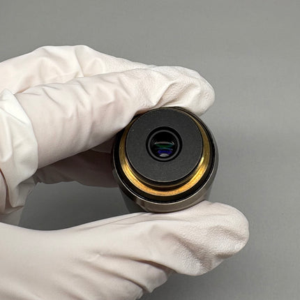 Hand holding the Olympus PlanApo 100x1.40 Oil ∞/0.17 RMS Thread Microscope Objective showing the lens end.