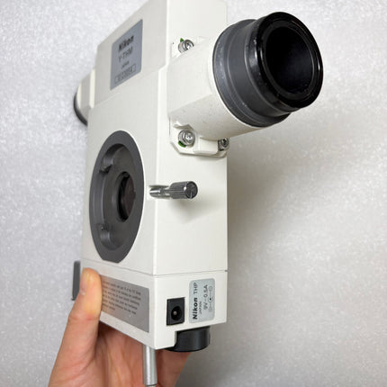 Nikon Microscope Y-THM Main Teaching Unit side view held by hand, showcasing its lens and attachment features.
